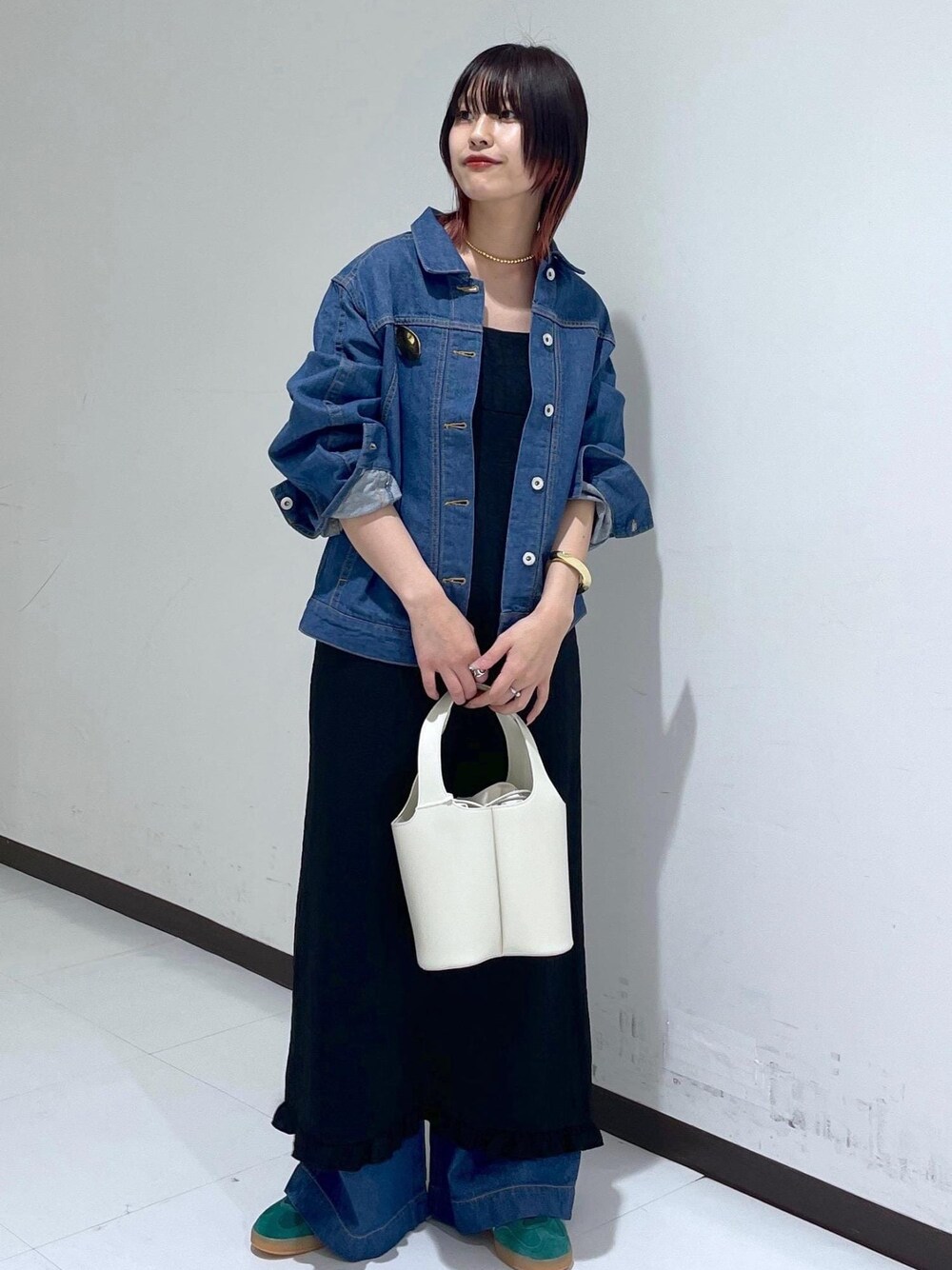 グリーン系のスニーカー、ブラック系のワンピース、ブルー系のブルゾンを着用したレディースの春コーディネートの1枚目の写真