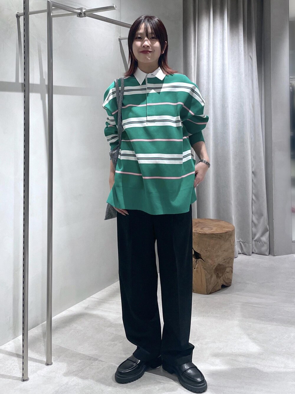 グリーン系のニット/セーター、ブラック系のスラックス、シルバー系のトートバッグを着用したレディースの冬コーディネートの1枚目の写真