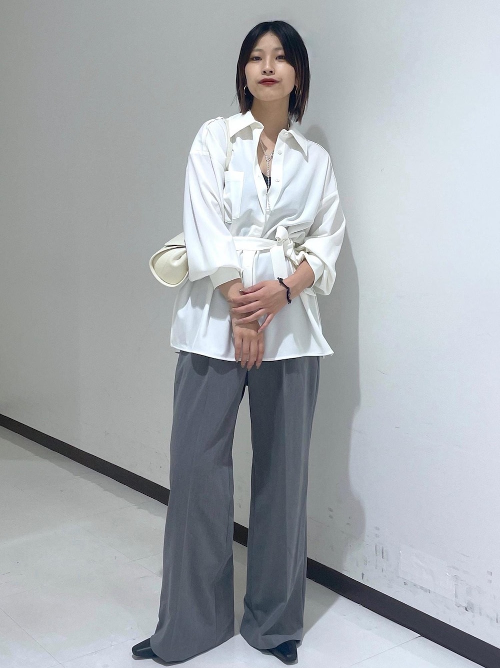 ホワイト系のシャツ/ブラウス、ホワイト系のショルダーバッグ、グレー系のスラックスを着用したレディースの夏コーディネートの1枚目の写真