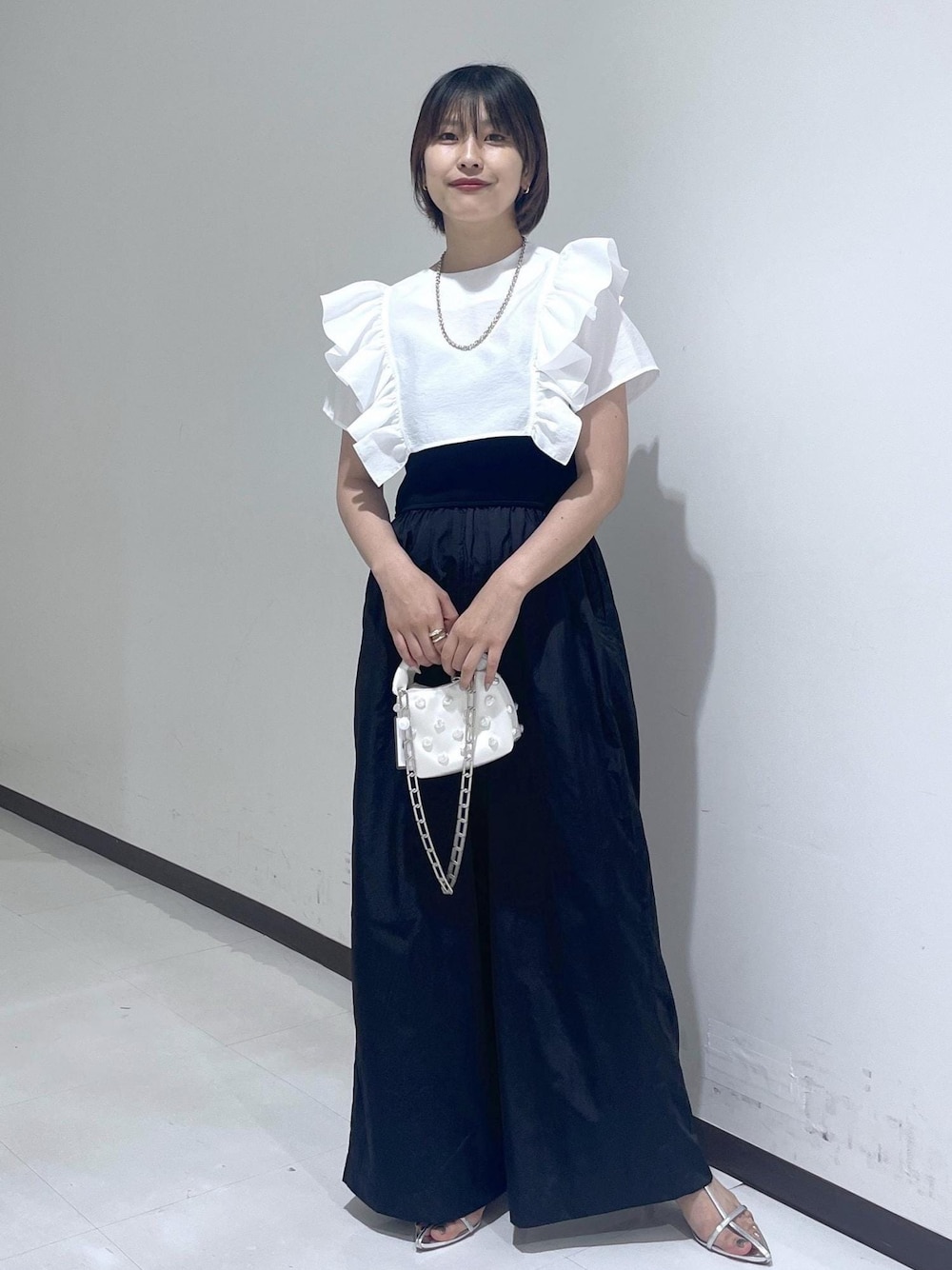 シルバー系のサンダル、ホワイト系のシャツ/ブラウス、ブラック系のつなぎ/オールインワンを着用したレディースの夏コーディネートの1枚目の写真