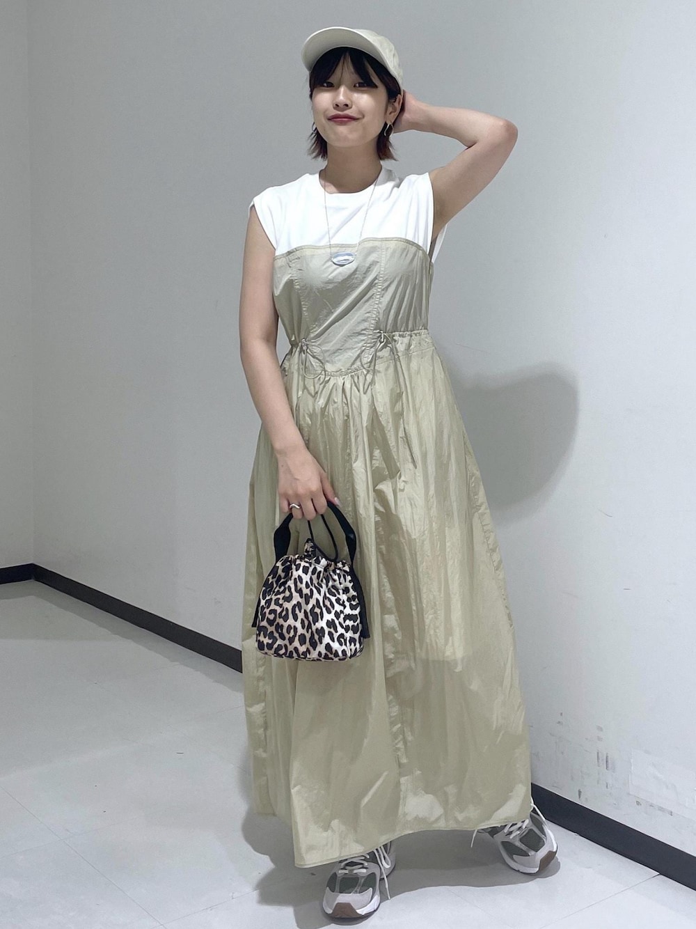 ブラウン系のハンドバッグ、ベージュ系のワンピース、ホワイト系のネックレスを着用したレディースの夏コーディネートの1枚目の写真