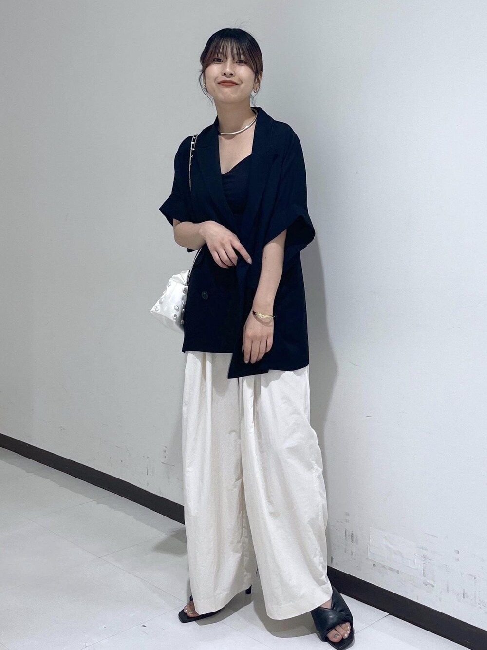 ブラック系のサンダル、ホワイト系のショルダーバッグ、ブラック系のテーラードジャケットを着用したレディースの春コーディネートの1枚目の写真