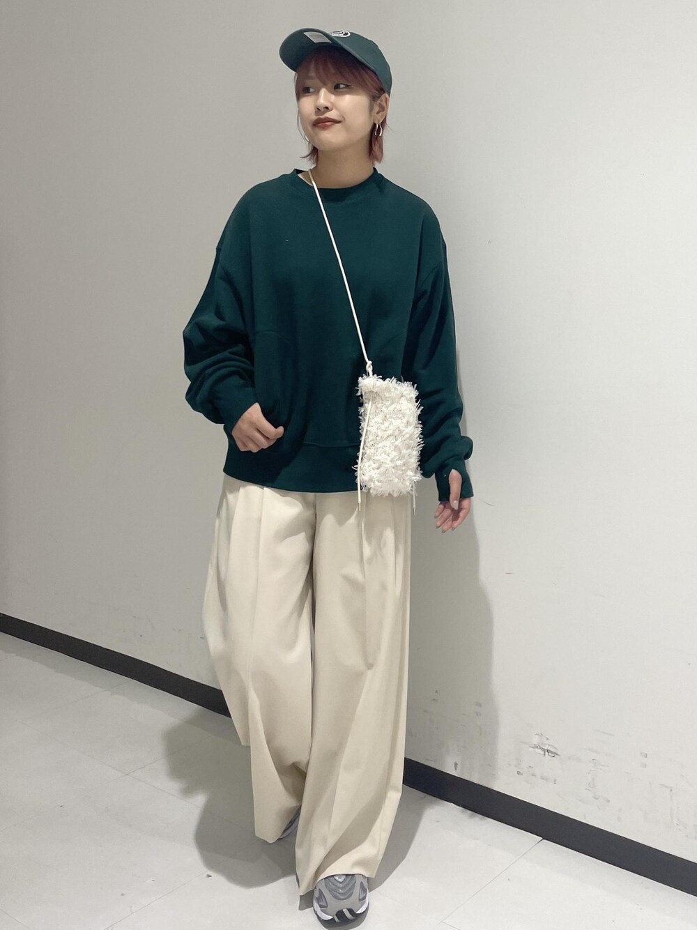 ホワイト系のスラックス、グリーン系のスウェット、ホワイト系のショルダーバッグを着用したレディースの秋コーディネートの1枚目の写真