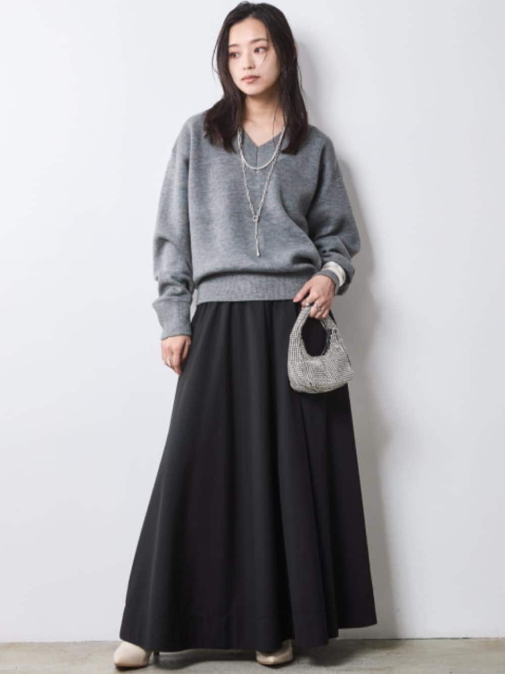 グレー系のニット/セーター、ブラック系のスカートを着用したレディースの秋コーディネートの1枚目の写真