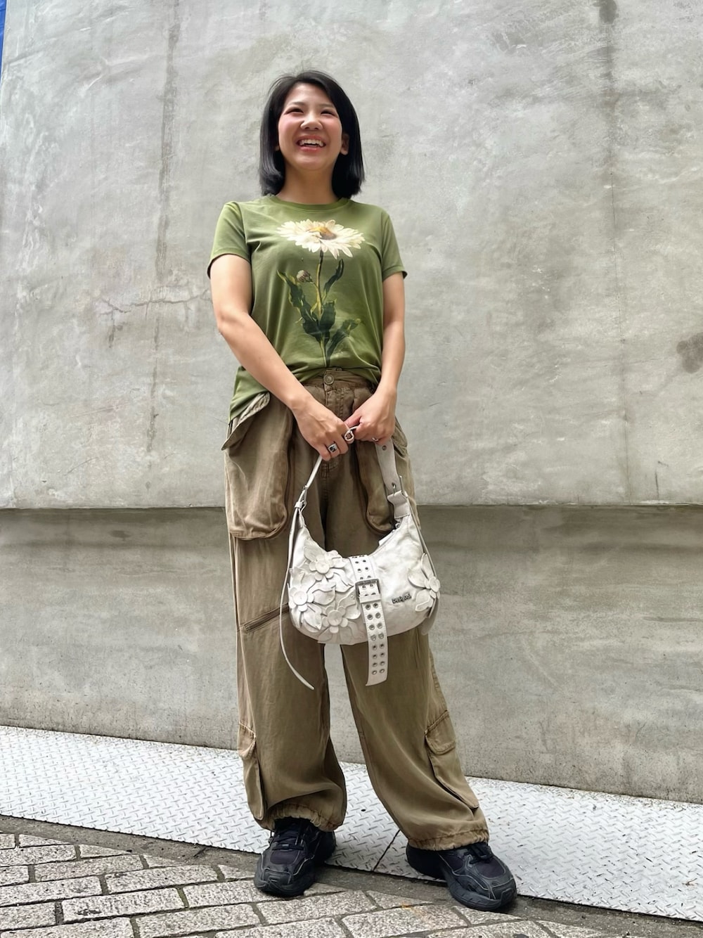 グリーン系のTシャツ/カットソー、ブラウン系のその他パンツ、ホワイト系のバッグを着用したレディースの春コーディネートの1枚目の写真