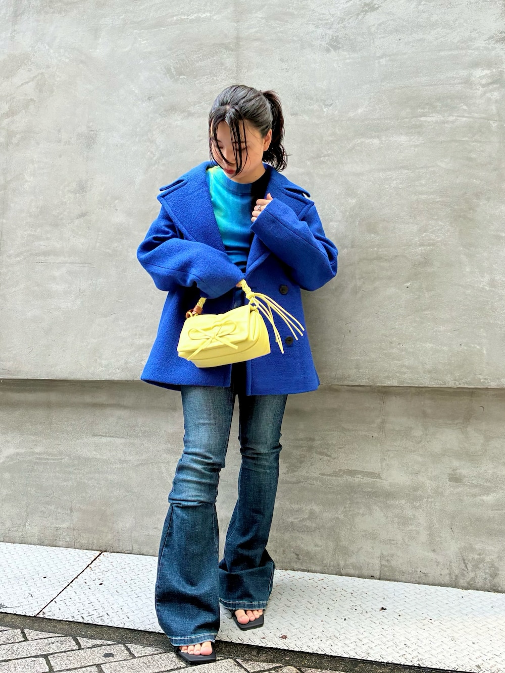 ブルー系のピーコート、ブルー系のデニムパンツ、ブラック系のサンダルを着用したレディースの秋コーディネートの1枚目の写真