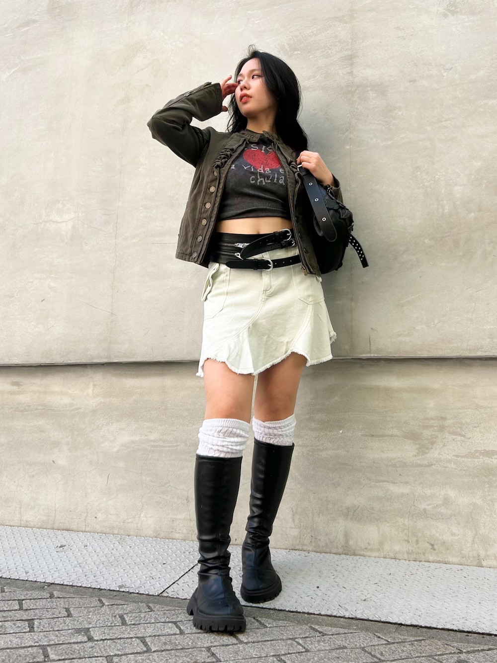 グリーン系のブルゾン、ホワイト系のスカート、ブラウン系のハンドバッグを着用したレディースの春コーディネートの1枚目の写真