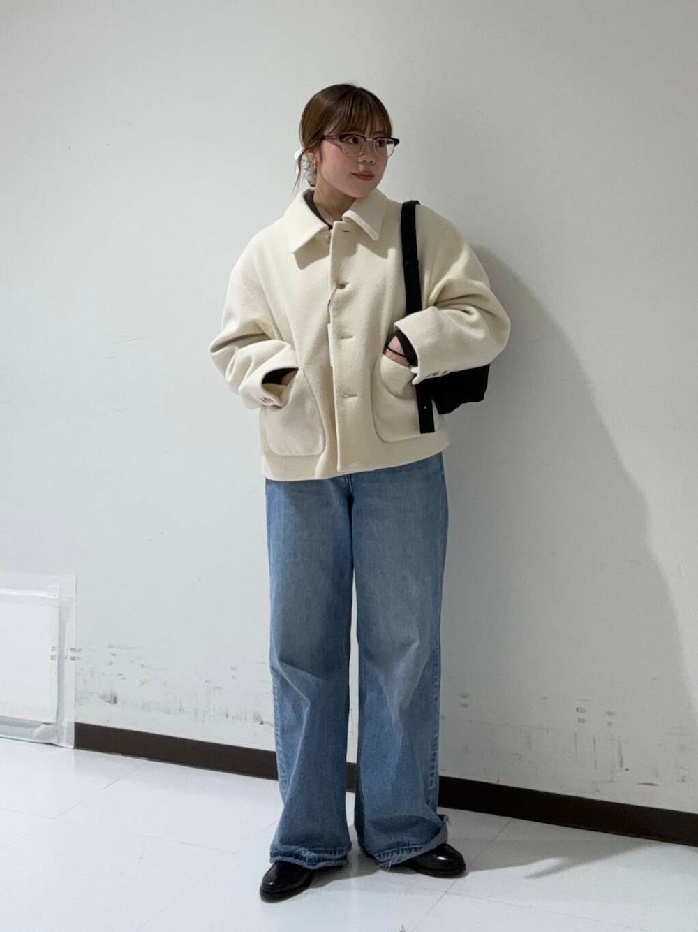 ブルー系のデニムパンツ、ブラウン系のニット/セーター、ホワイト系のその他アウターを着用したレディースの冬コーディネートの1枚目の写真