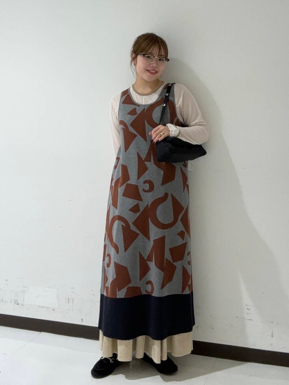 グレー系のTシャツ/カットソー、グレー系のニット/セーター、ブラック系のハンドバッグを着用したレディースの秋コーディネートの1枚目の写真