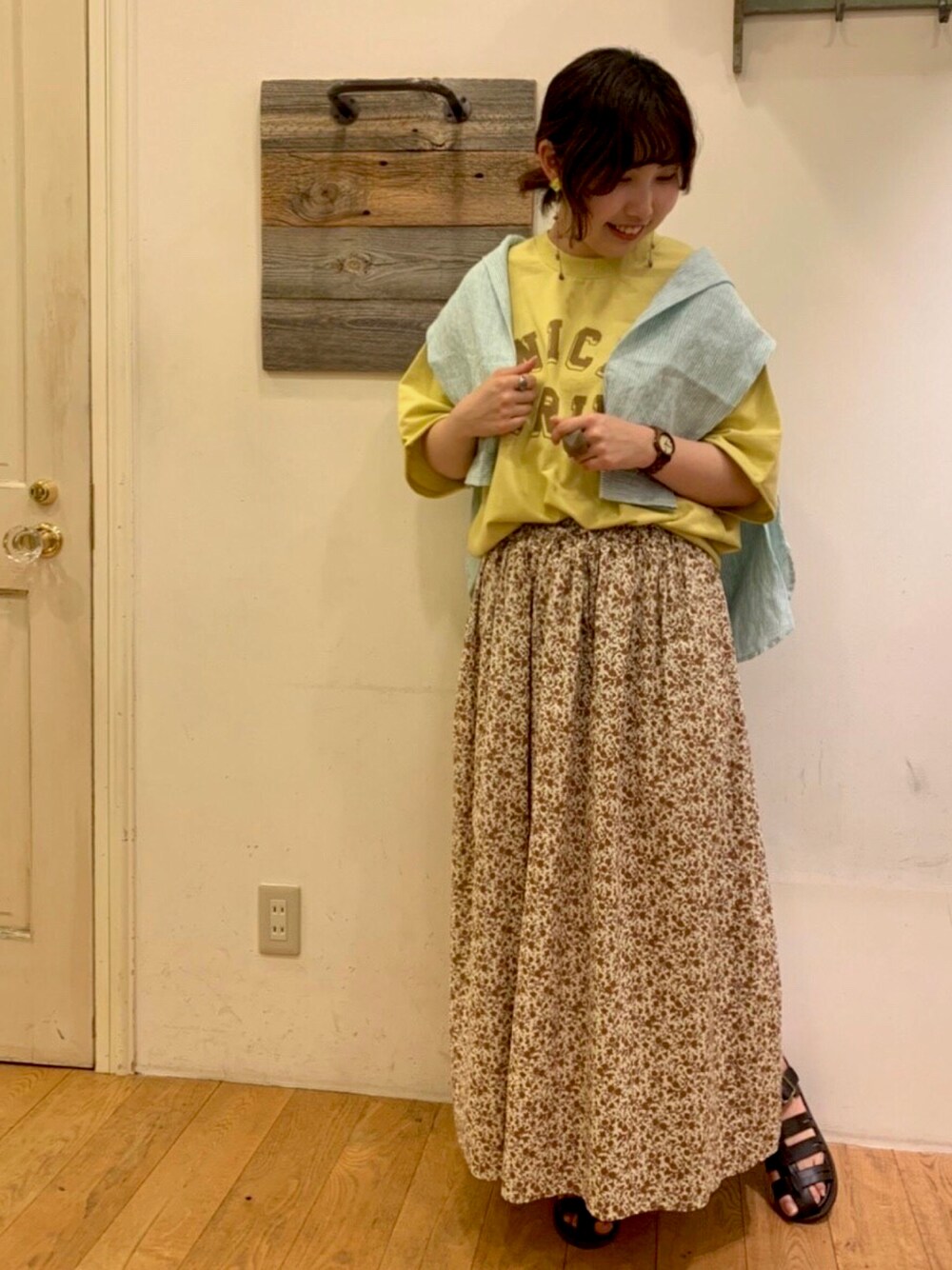 オレンジ系のスカート、ブラック系のサンダル、グリーン系のシャツ/ブラウスを着用したレディースの春コーディネートの1枚目の写真