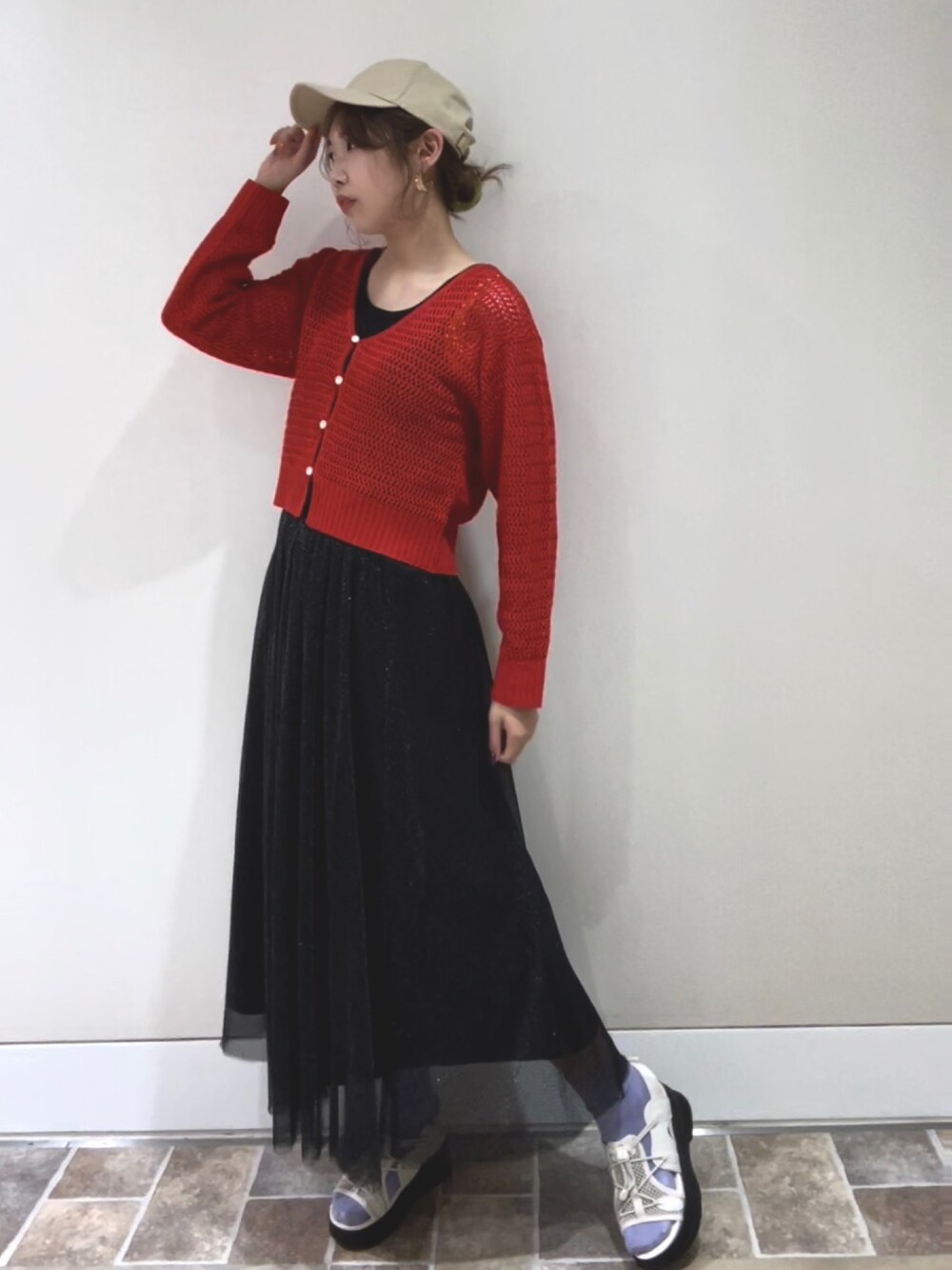 レッド系のカーディガン/ボレロ、ブラック系のスカート、ホワイト系のサンダルを着用したレディースの春コーディネートの1枚目の写真