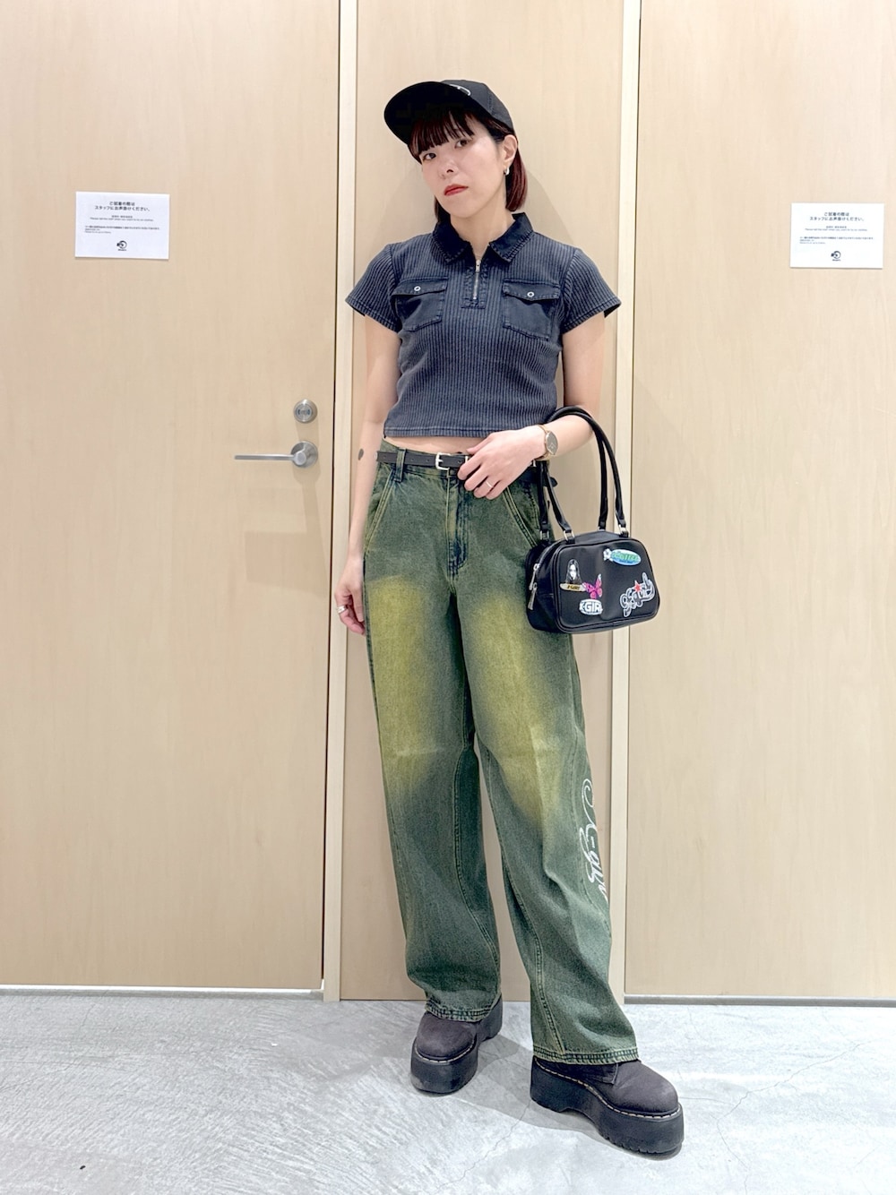 ブラック系のハンドバッグ、ブラック系のポロシャツ、ブルー系のデニムパンツを着用したレディースの夏コーディネートの1枚目の写真