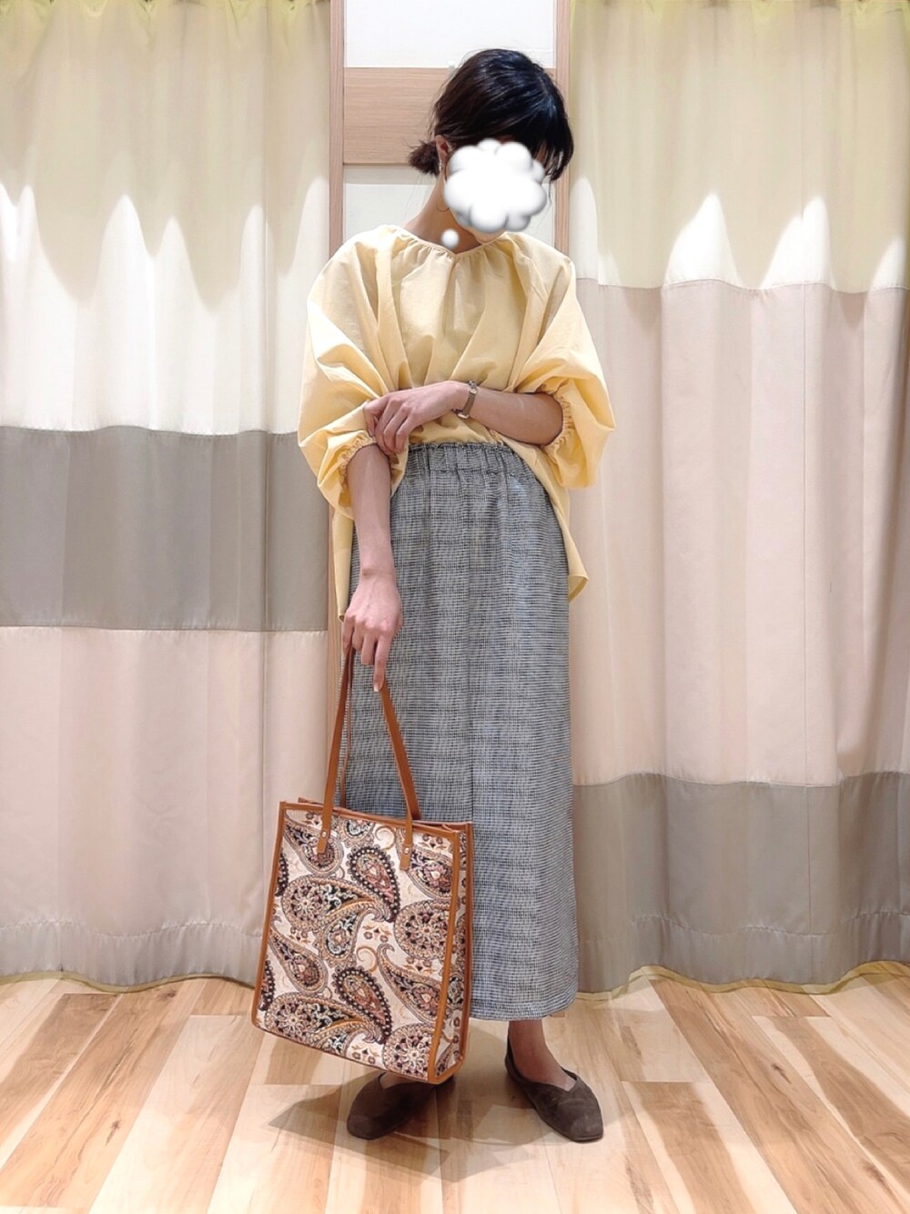 ブラウン系のトートバッグ、ホワイト系のスカート、ベージュ系のTシャツ/カットソーを着用したレディースの春コーディネートの1枚目の写真