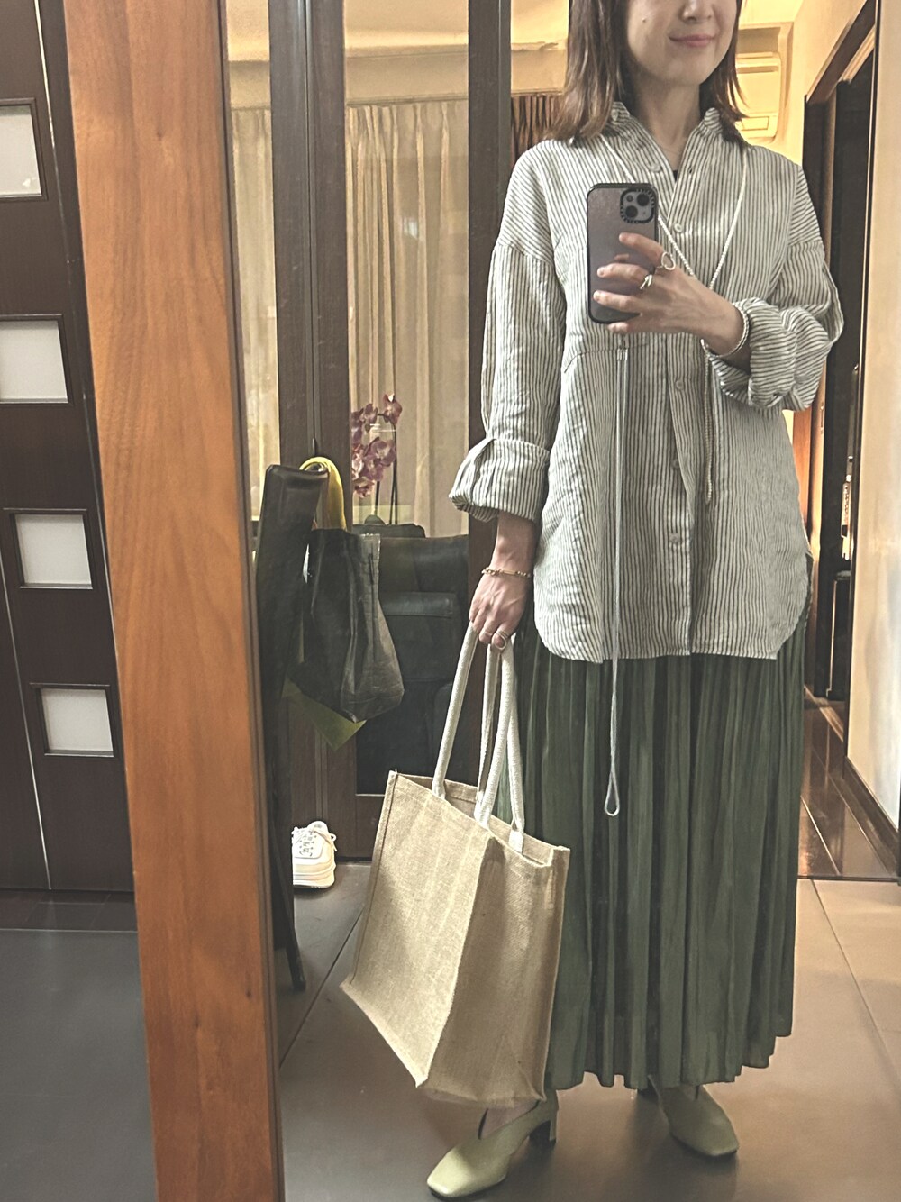 ベージュ系のシャツ/ブラウス、グリーン系のスカート、イエロー系のパンプスを着用したレディースの春コーディネートの1枚目の写真