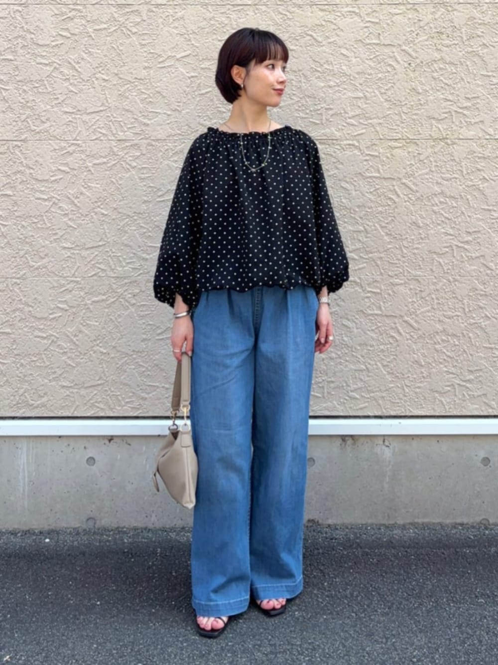 ブルー系のデニムパンツ、ブラック系のシャツ/ブラウス、ベージュ系のハンドバッグを着用したレディースの夏コーディネートの1枚目の写真