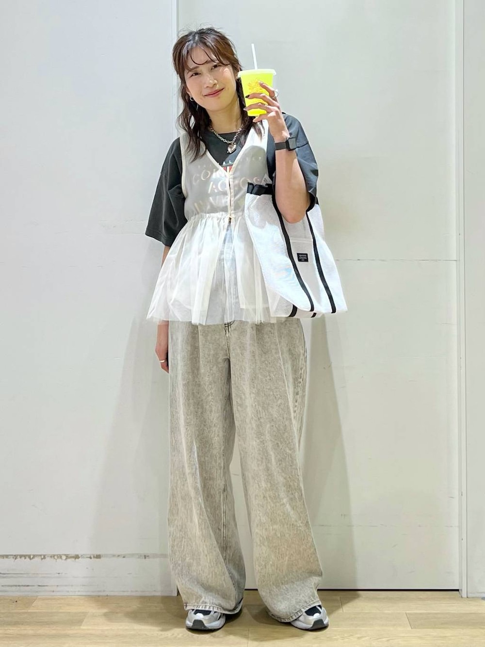 グレー系のデニムパンツ、ベージュ系のベスト、グレー系のTシャツ/カットソーを着用したレディースの春コーディネートの1枚目の写真