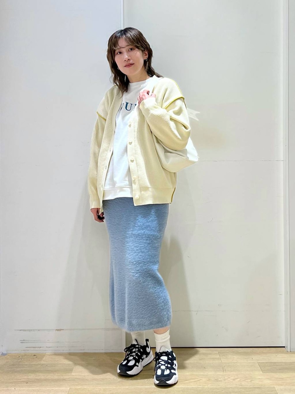 ホワイト系のショルダーバッグ、ブルー系のスカート、ホワイト系のカーディガン/ボレロを着用したレディースの冬コーディネートの1枚目の写真