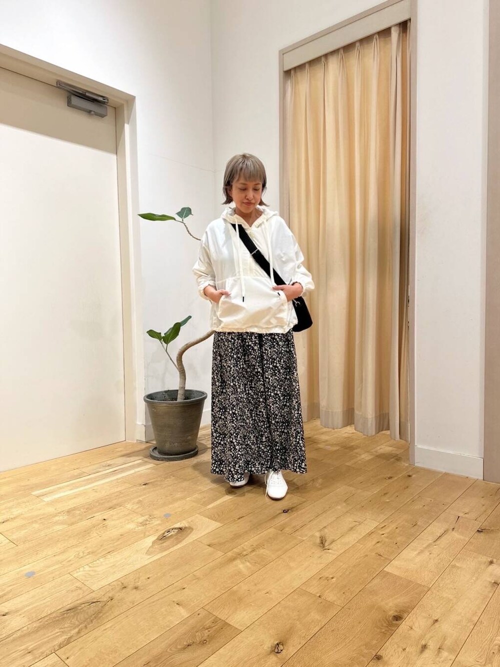 ブラック系のショルダーバッグ、ホワイト系のパーカー、ブラック系のスカートを着用したレディースの春コーディネートの1枚目の写真