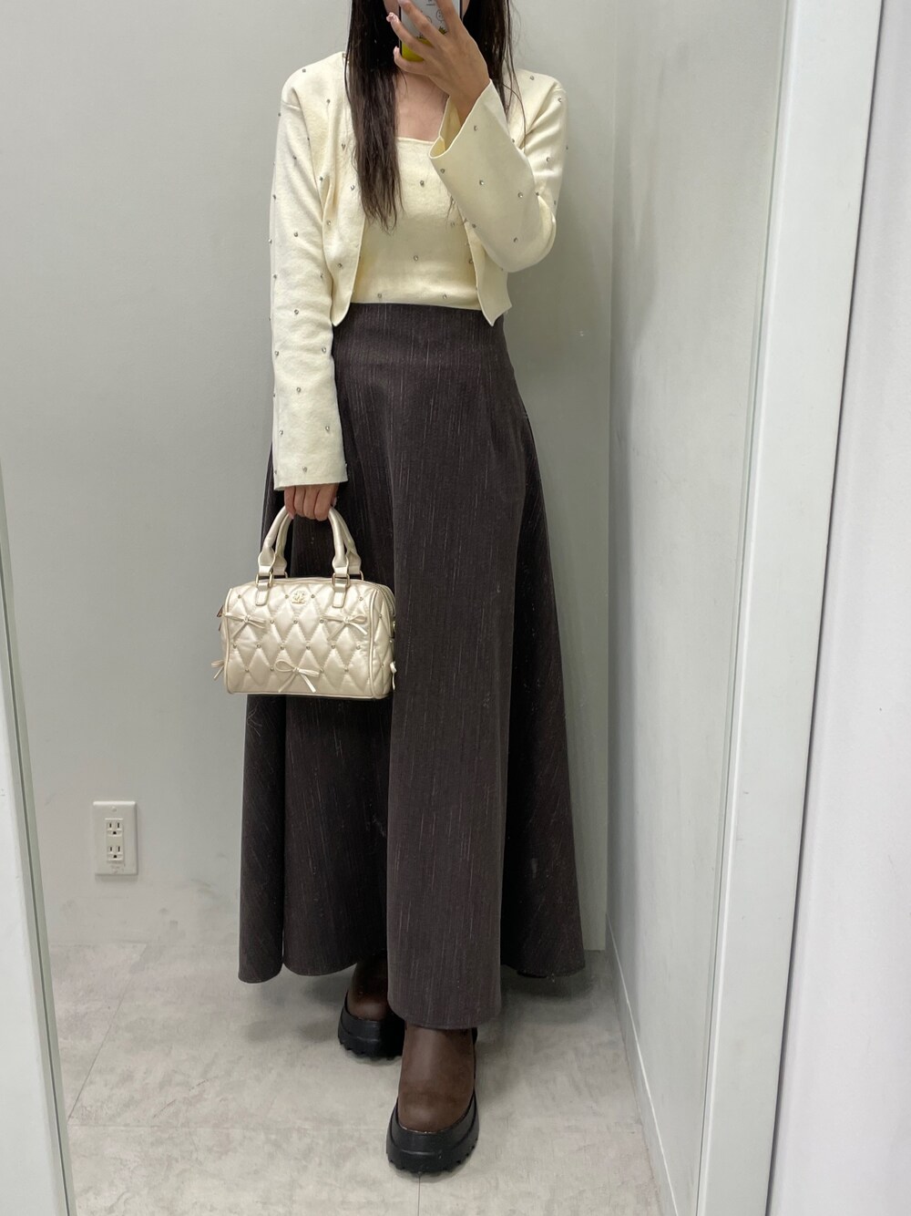 ホワイト系のカーディガン/ボレロ、ホワイト系のキャミソール、ブラウン系のスカートを着用したレディースの秋コーディネートの1枚目の写真