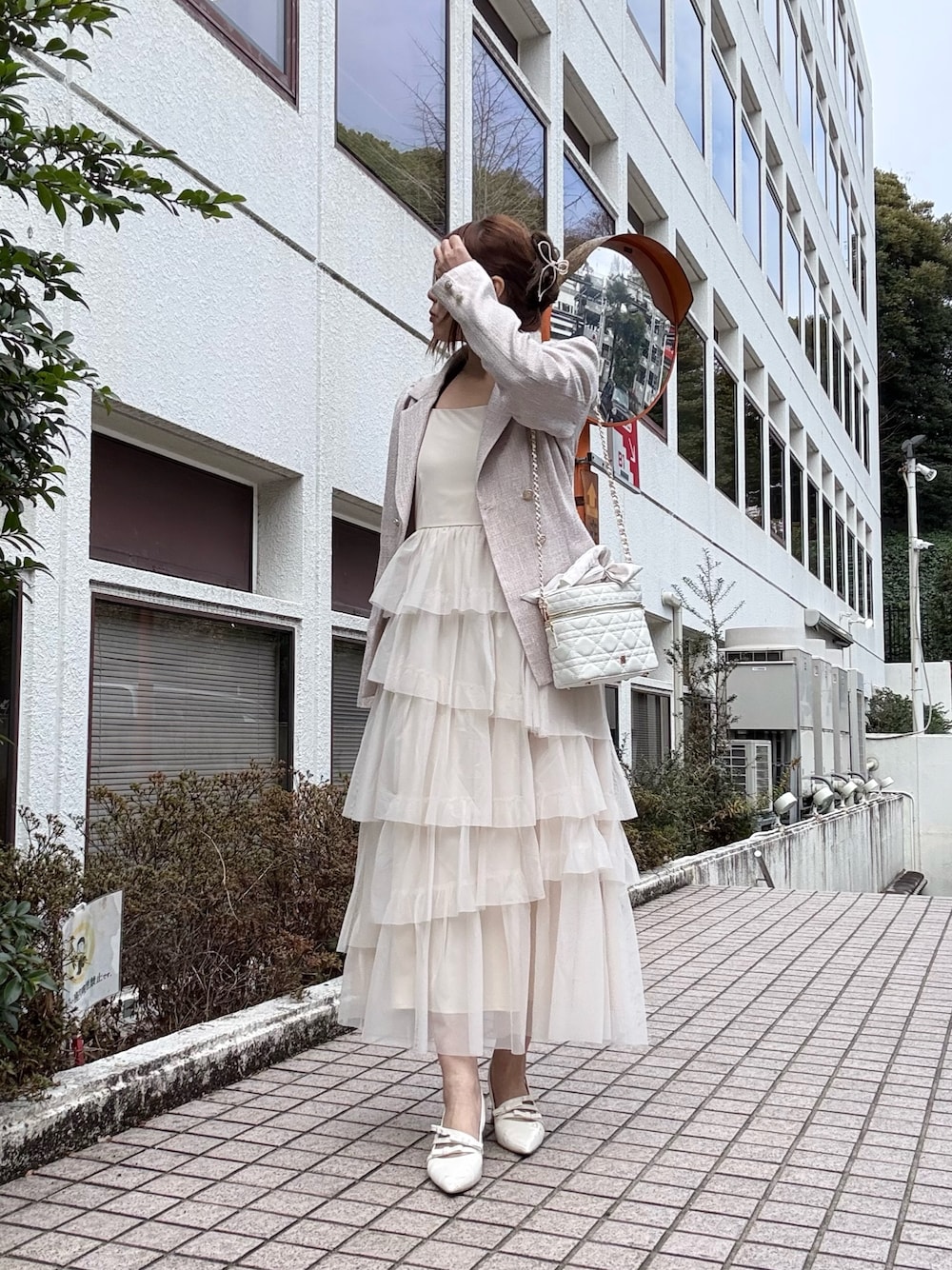 ピンク系のテーラードジャケット、ホワイト系のワンピース、ホワイト系のショルダーバッグを着用したレディースの冬コーディネートの1枚目の写真