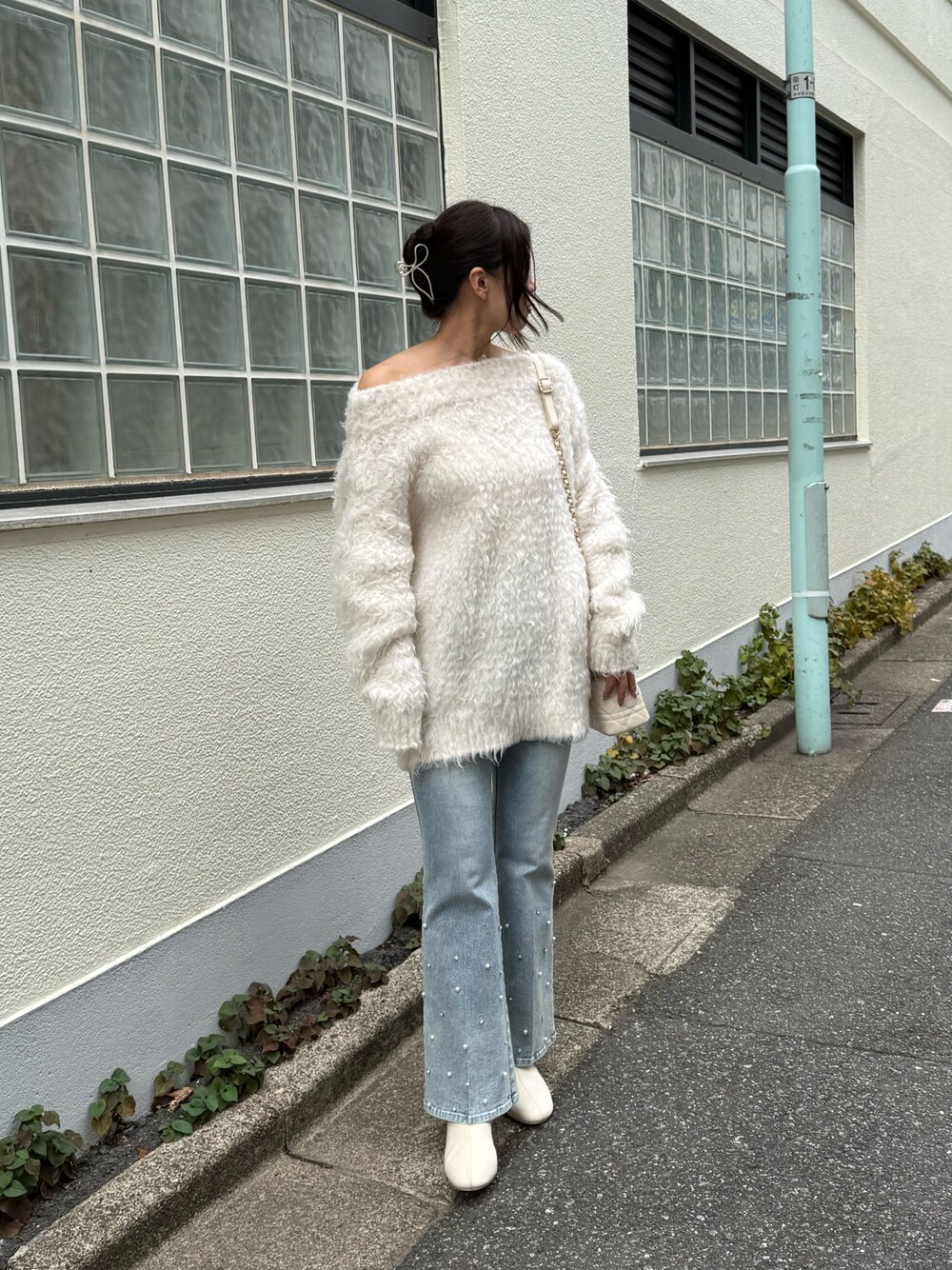 ホワイト系のニット/セーター、ブルー系のデニムパンツ、ホワイト系のショルダーバッグを着用したレディースの秋コーディネートの1枚目の写真