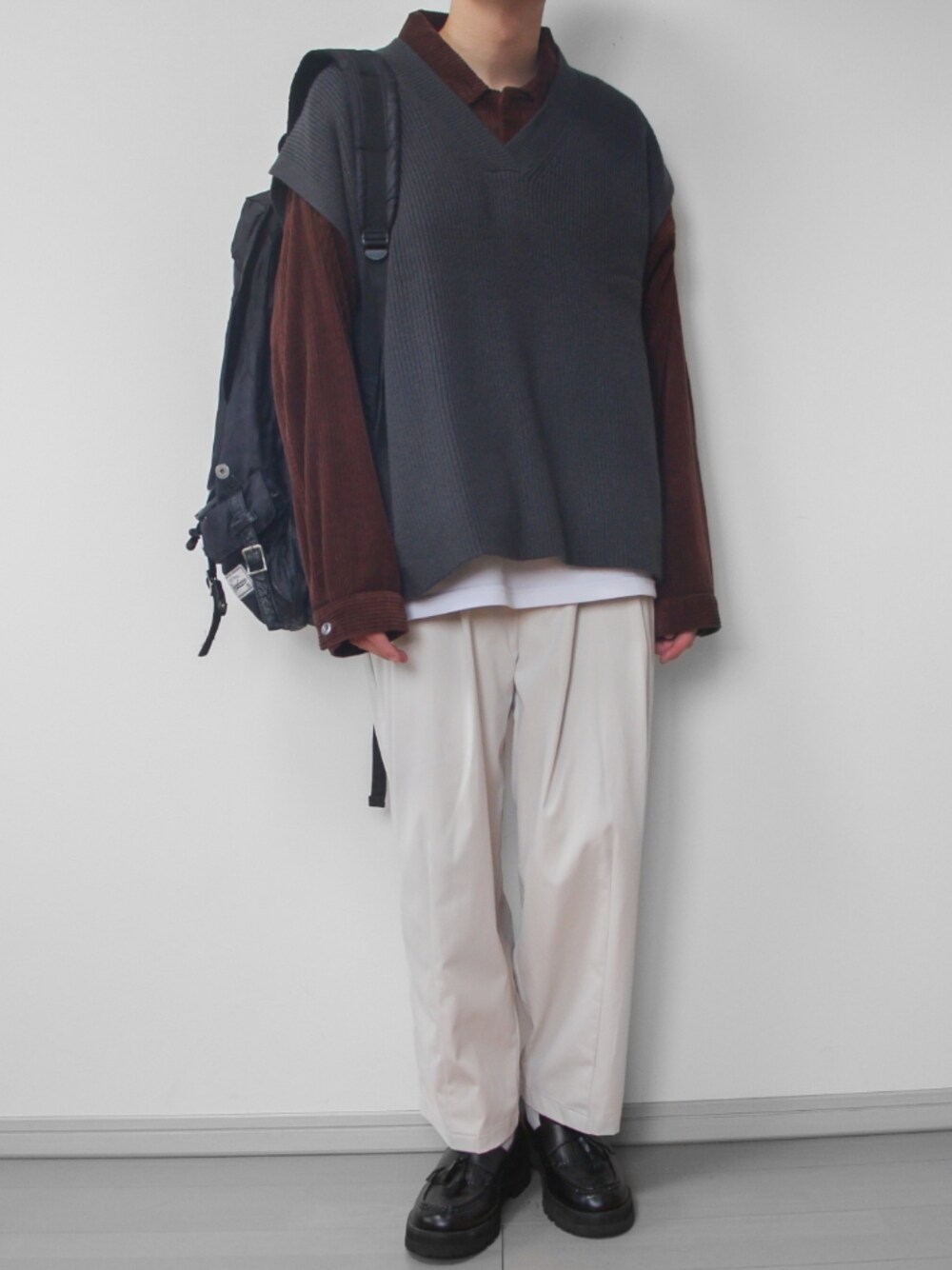 ホワイト系のその他パンツ、ブラック系のローファー、グレー系のベストを着用したメンズの秋コーディネートの1枚目の写真