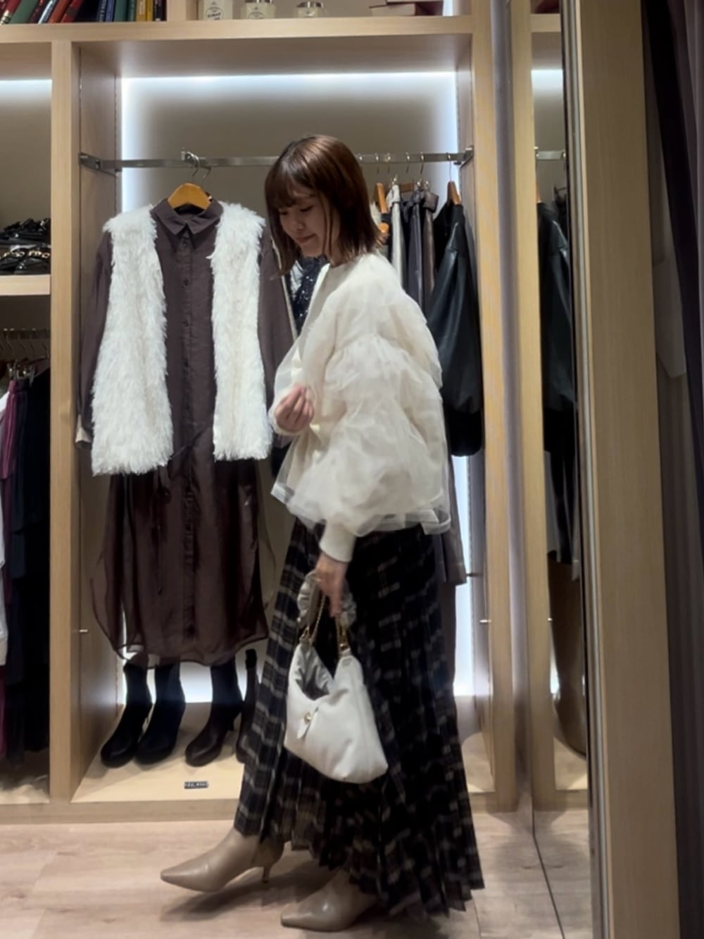 ホワイト系のTシャツ/カットソー、ブルー系のスカート、ホワイト系のハンドバッグを着用したレディースの秋コーディネートの1枚目の写真