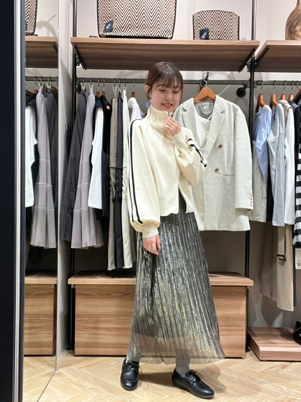 ホワイト系のニット/セーター、ブルー系のスカート、ブラック系のその他シューズを着用したレディースの春コーディネートの1枚目の写真