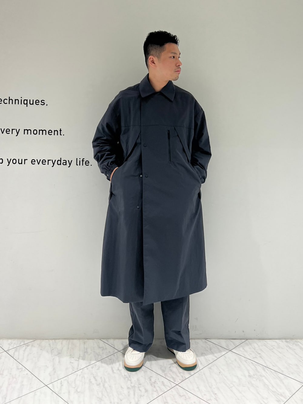 グレー系のチェスターコート、グレー系のスラックスを着用したメンズの秋コーディネートの1枚目の写真