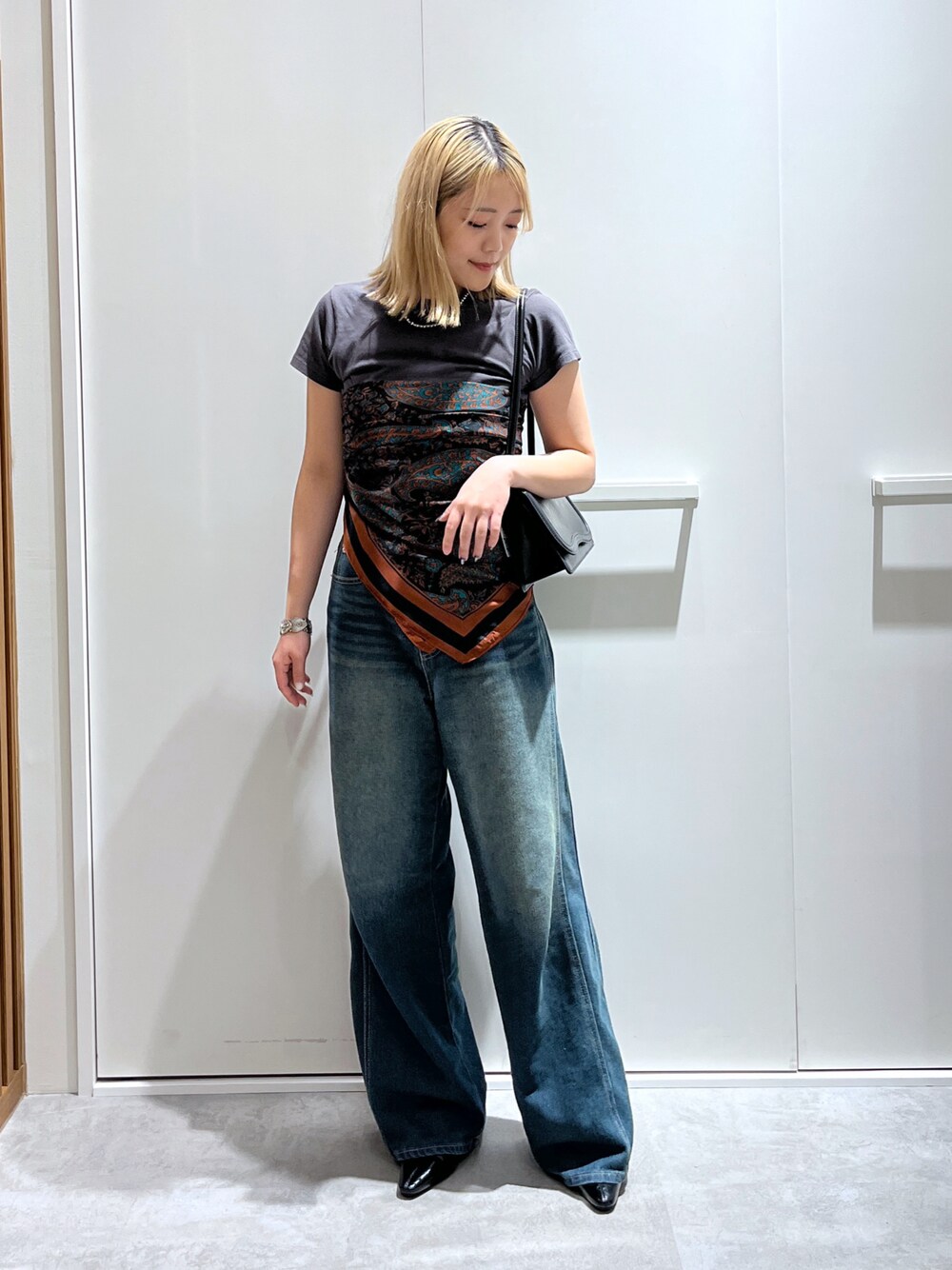 グレー系のTシャツ/カットソー、ブルー系のデニムパンツ、ブラック系のショルダーバッグを着用したレディースの秋コーディネートの1枚目の写真