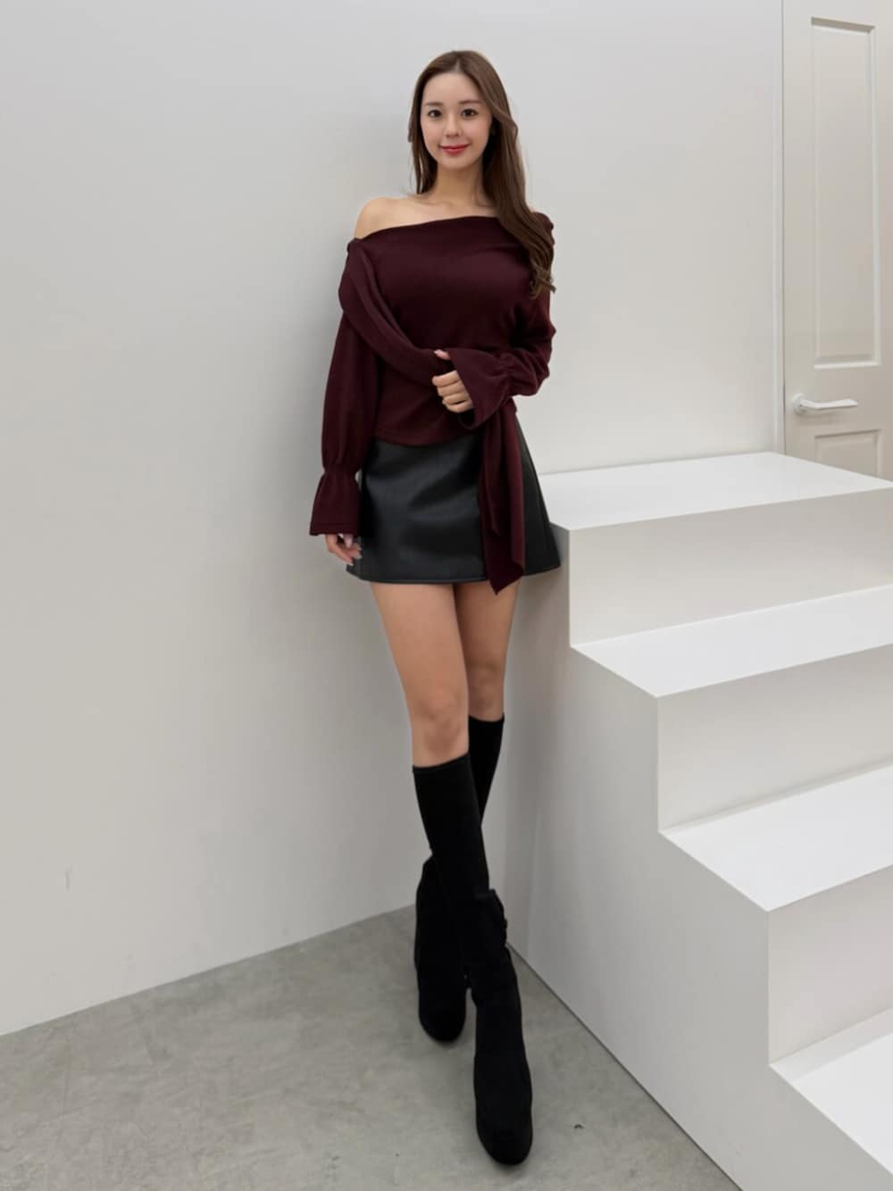 ブラック系のブーツ、ブラック系のスカート、レッド系のTシャツ/カットソーを着用したレディースの冬コーディネートの1枚目の写真