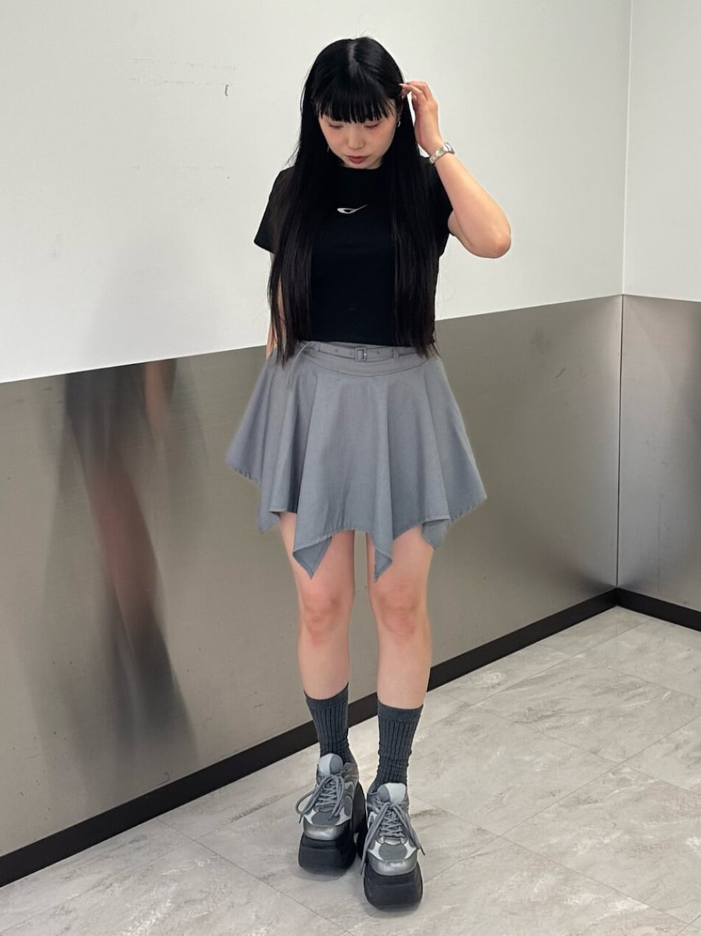 シルバー系のスニーカー、グレー系のスカート、ブラック系のTシャツ/カットソーを着用したレディースの春コーディネートの1枚目の写真