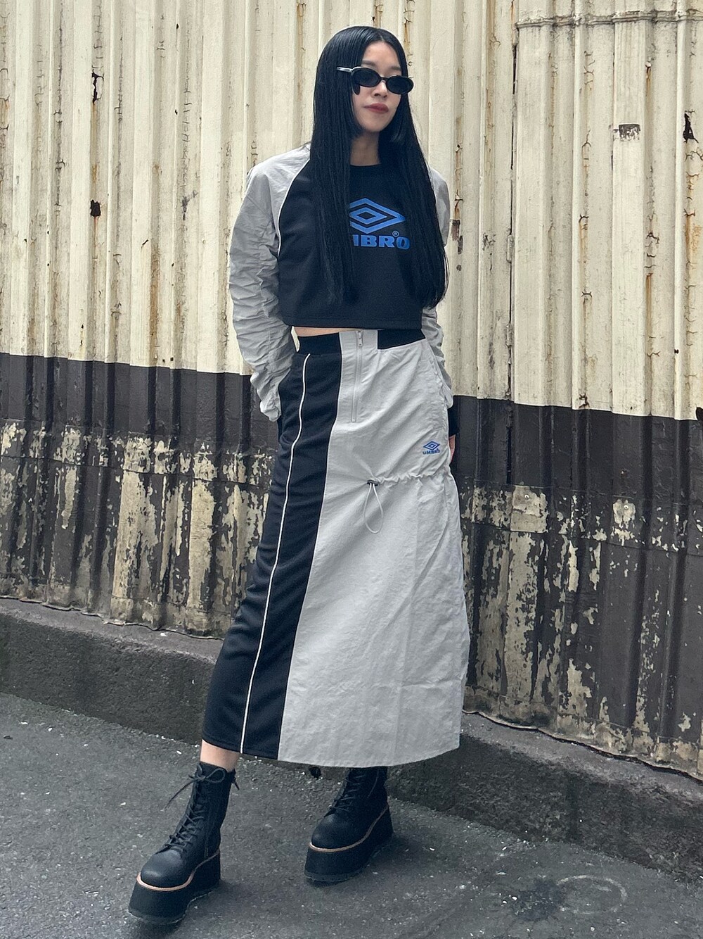 グレー系のTシャツ/カットソー、グレー系のスカート、ブラック系のブーツを着用したレディースの秋コーディネートの1枚目の写真