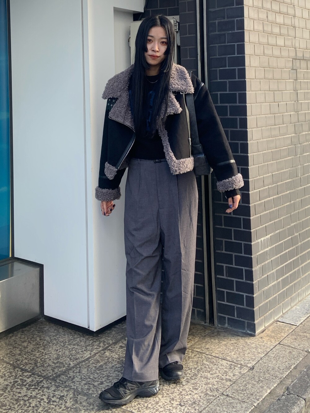ブラック系のニット/セーター、グレー系のその他パンツ、ブラック系のムートンコートを着用したレディースの冬コーディネートの1枚目の写真