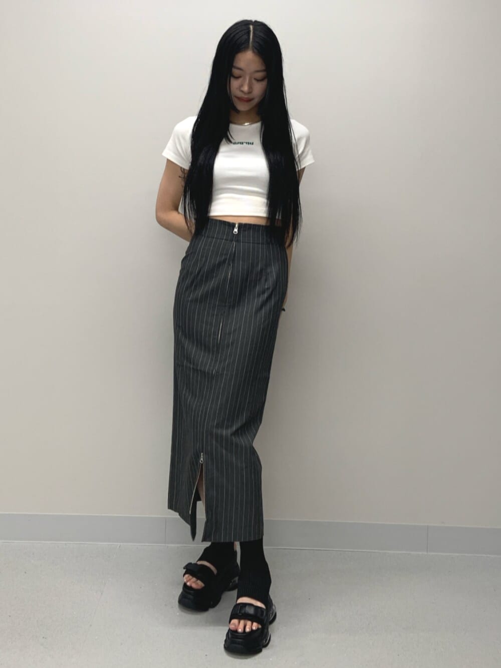 ブラック系のサンダル、ホワイト系のTシャツ/カットソー、グレー系のスカートを着用したレディースの春コーディネートの1枚目の写真