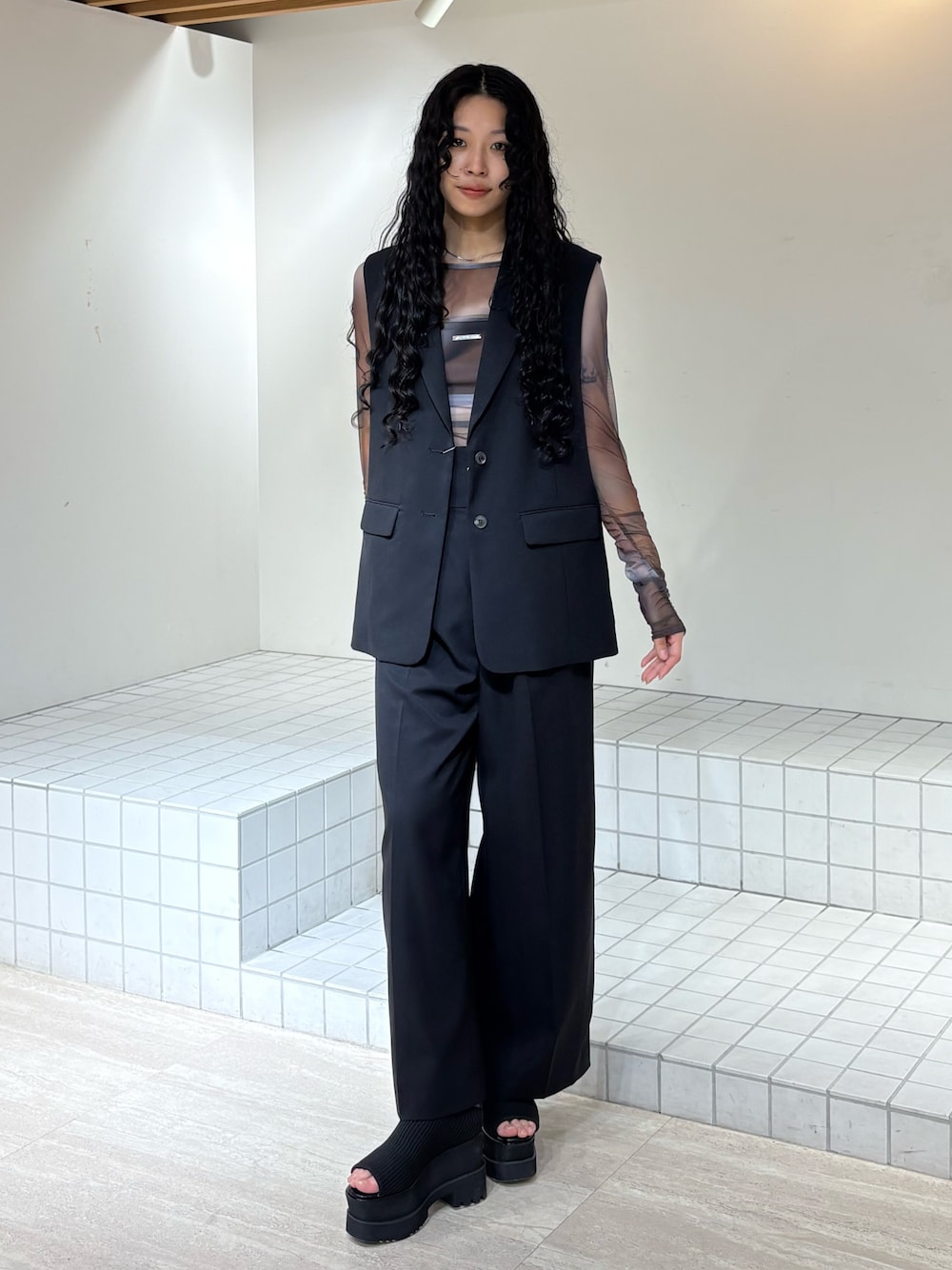 ブラック系のベスト、ブラック系のスラックス、ブラウン系のTシャツ/カットソーを着用したレディースの春コーディネートの1枚目の写真