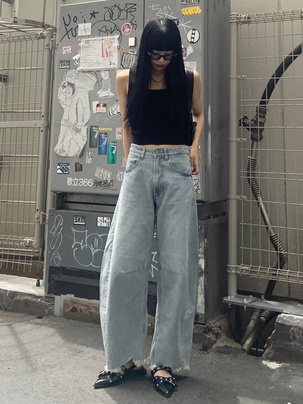 ブラック系のニット/セーター、ブルー系のデニムパンツ、ブラック系のパンプスを着用したレディースの夏コーディネートの1枚目の写真