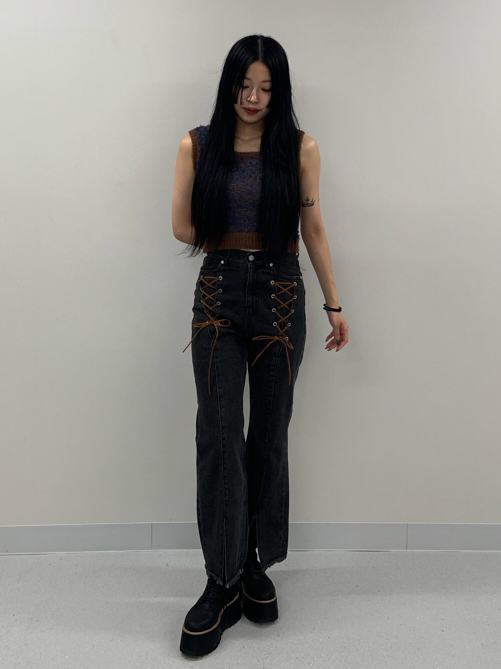 ブラック系のデニムパンツ、ブラック系のブーツ、ブラウン系のニット/セーターを着用したレディースの夏コーディネートの1枚目の写真