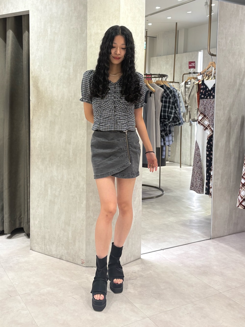 ブラック系のデニムスカート、ブラック系のブーツを着用したレディースの夏コーディネートの1枚目の写真