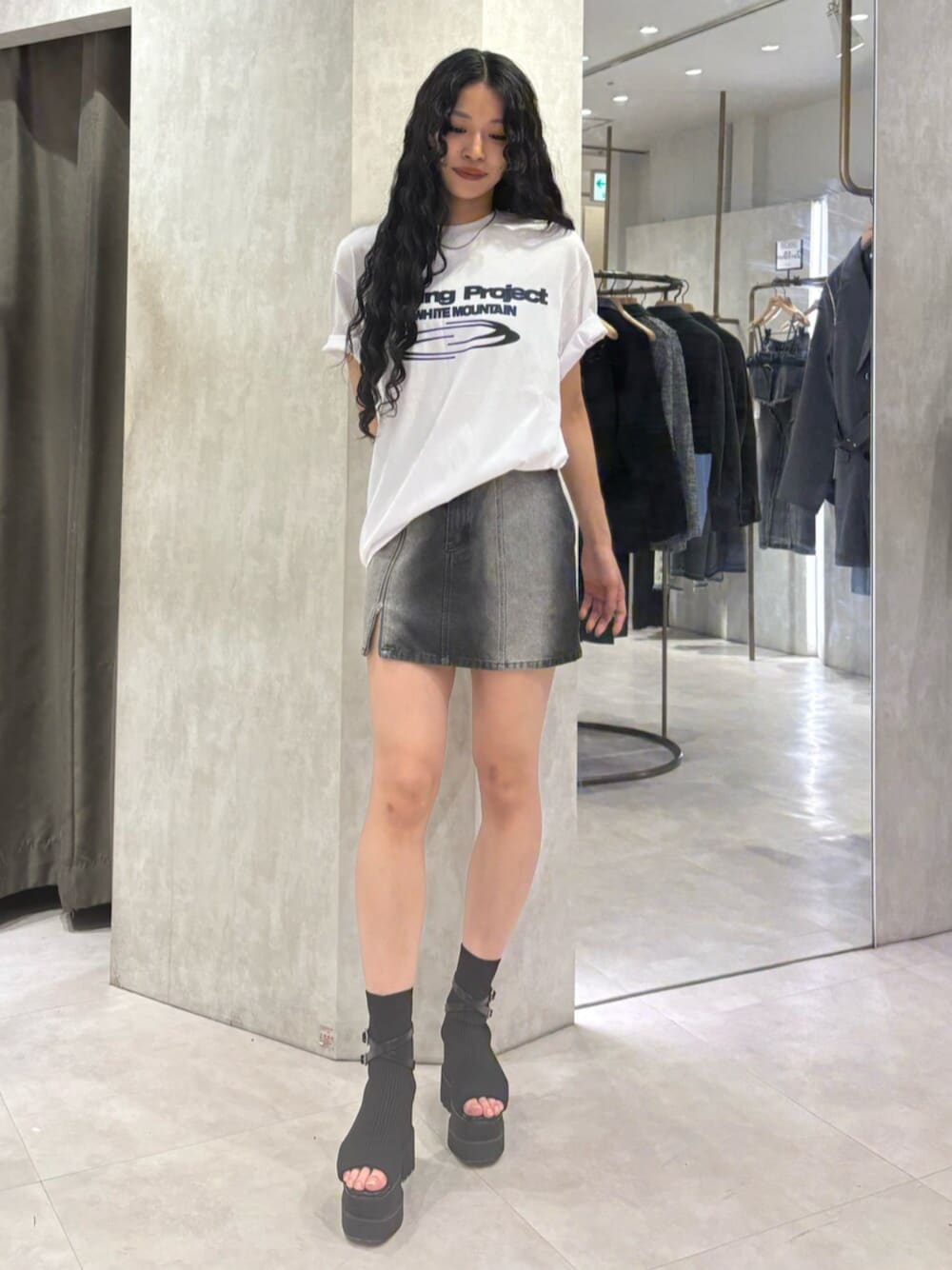ブラック系のブーツ、ブラック系のデニムスカート、ホワイト系のTシャツ/カットソーを着用したレディースの春コーディネートの1枚目の写真