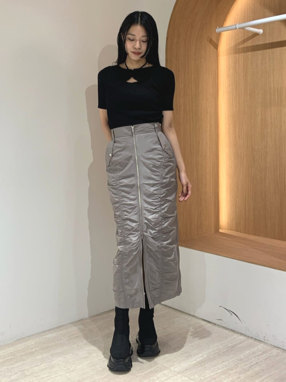 ブラック系のブーツ、ブラック系のニット/セーター、グレー系のスカートを着用したレディースの春コーディネートの1枚目の写真