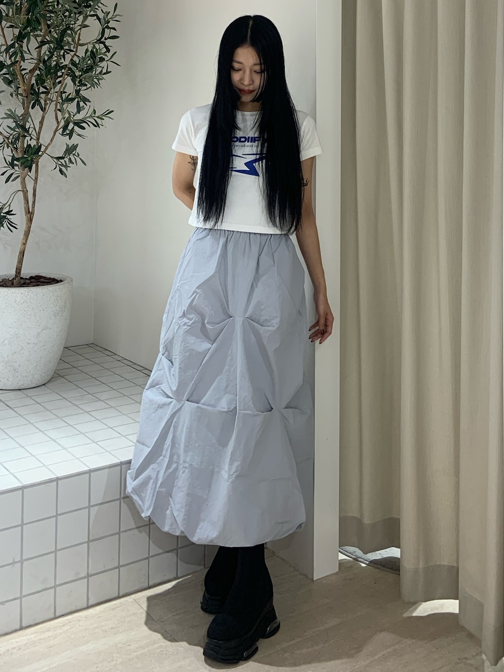 ホワイト系のTシャツ/カットソー、ブルー系のスカート、ブラック系のブーツを着用したレディースの春コーディネートの1枚目の写真