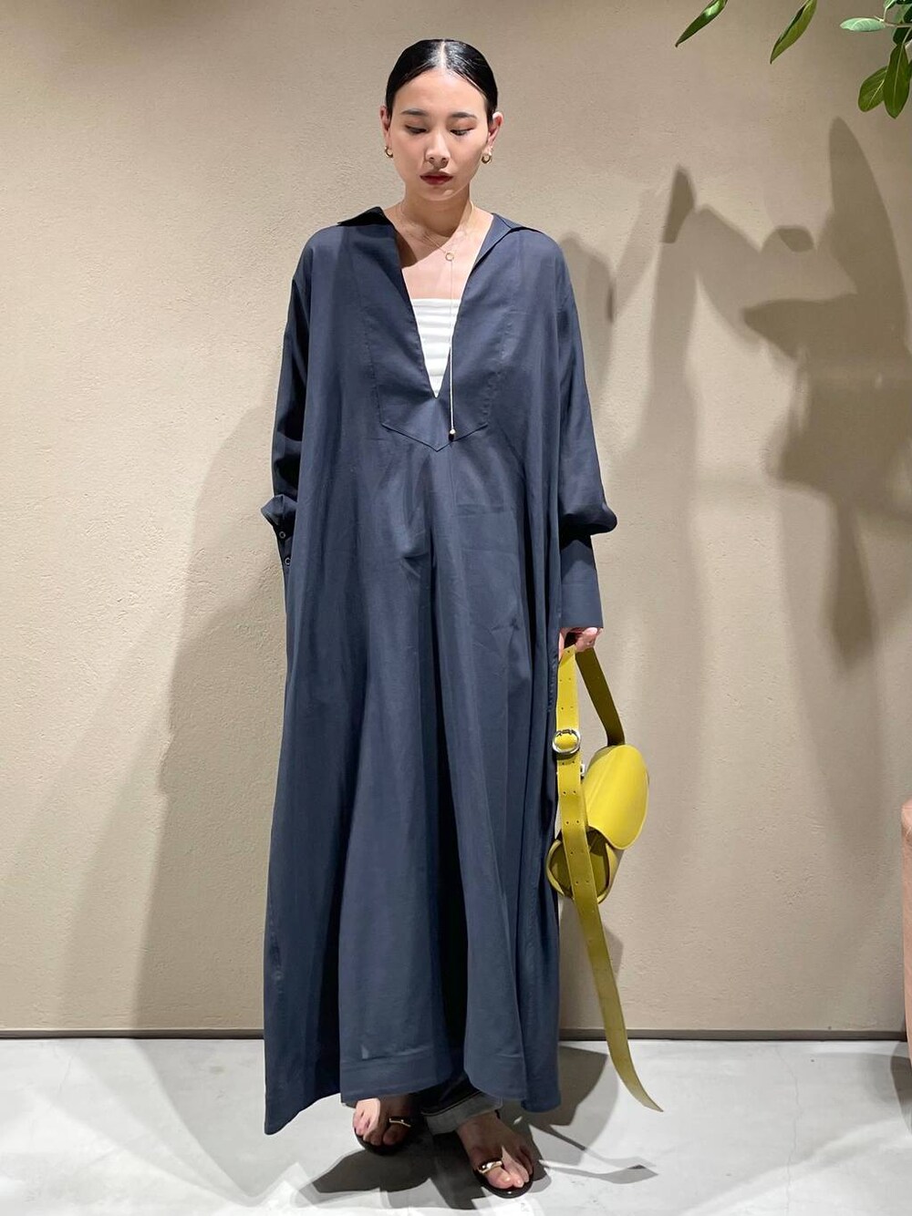ブルー系のデニムパンツ、ホワイト系のチューブトップ、グレー系のワンピースを着用したレディースの春コーディネートの1枚目の写真