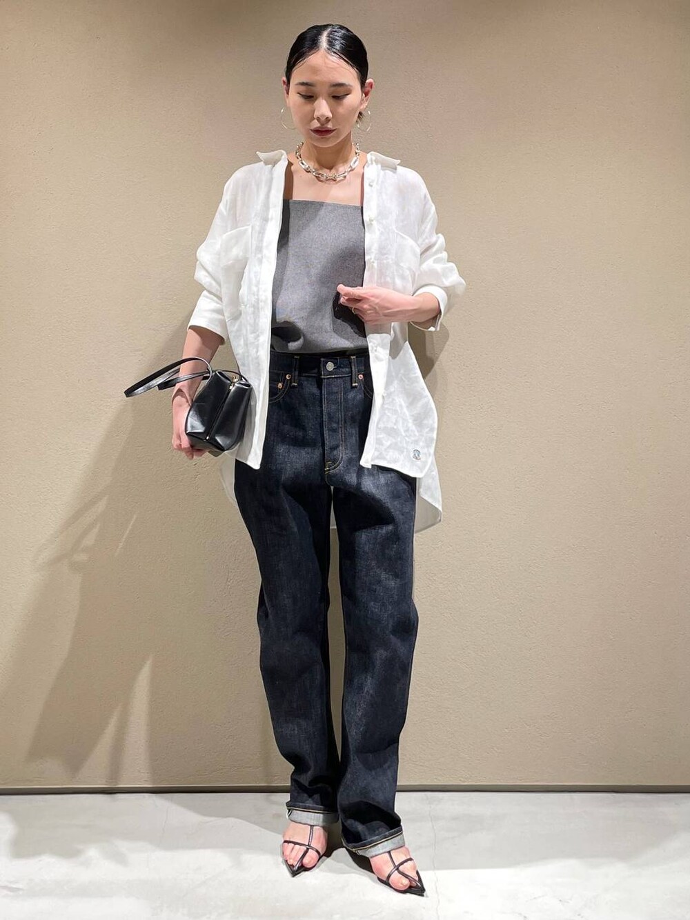 ブルー系のデニムパンツ、ホワイト系のシャツ/ブラウス、ブラック系のベストを着用したレディースの春コーディネートの1枚目の写真