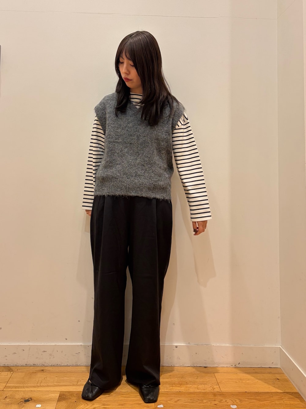 グレー系のベスト、ホワイト系のTシャツ/カットソー、ブラック系のその他パンツを着用したレディースの秋コーディネートの1枚目の写真
