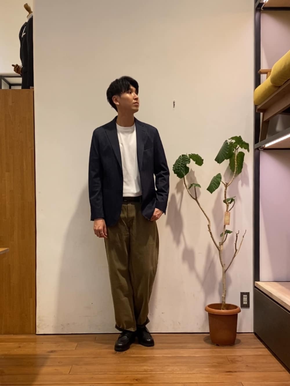 ブラウン系のデニムパンツ、ブラック系のドレスシューズ、ホワイト系のTシャツ/カットソーを着用したメンズの秋コーディネートの1枚目の写真