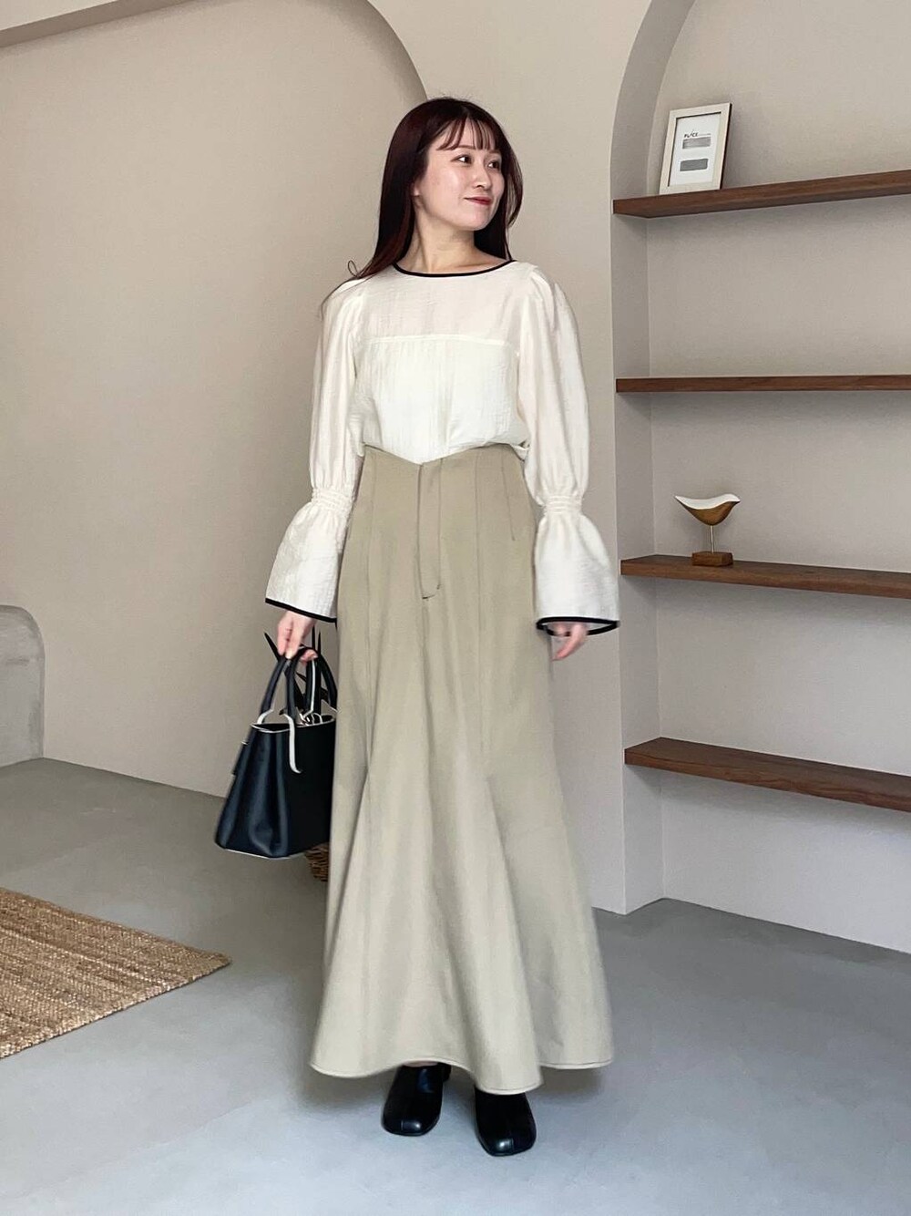 ブラック系のショルダーバッグ、ホワイト系のシャツ/ブラウス、ブラック系のパンプスを着用したレディースの春コーディネートの1枚目の写真