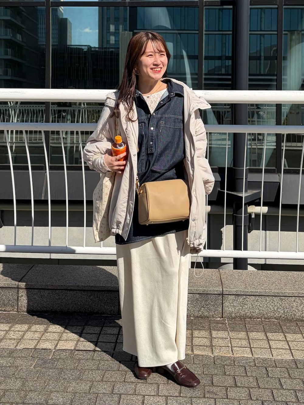 ホワイト系のスカート、ゴールド系のボストンバッグ、ホワイト系のTシャツ/カットソーを着用したレディースの冬コーディネートの1枚目の写真