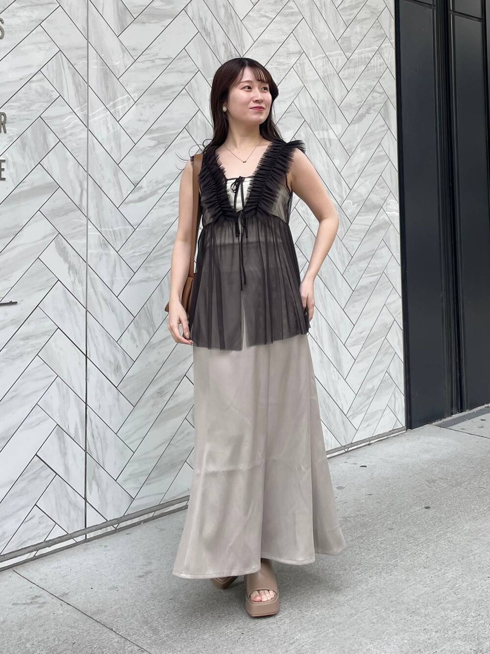 ホワイト系のキャミソール、ベージュ系のサンダル、ブラウン系のショルダーバッグを着用したレディースの夏コーディネートの1枚目の写真