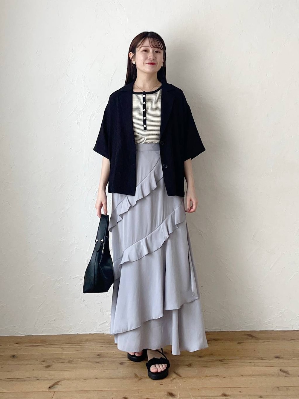 ブラック系のサンダル、グレー系のスカート、ブラック系のショルダーバッグを着用したレディースの夏コーディネートの1枚目の写真